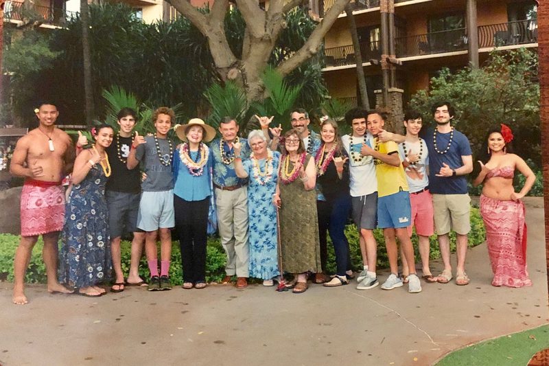 Lucas' family and some friends posing for a photo at a Hawaiian luau; Lucas and Larry are standing to the right