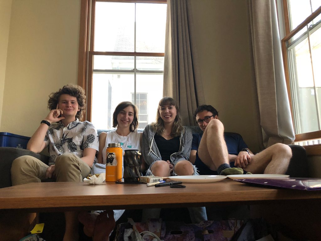 four students sit on a couch in living room