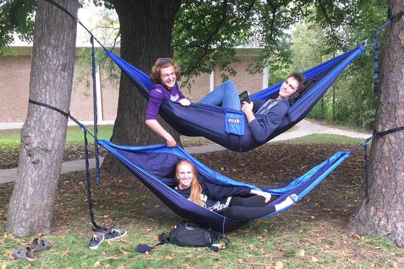 Three students hang out in two hammocks