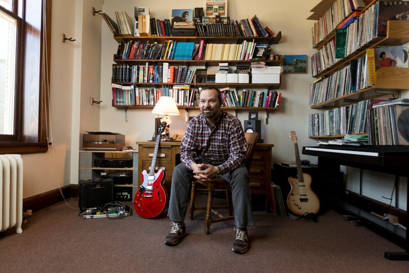 Professor Andy Flory in his office, surrounded by books, albums, and guitars