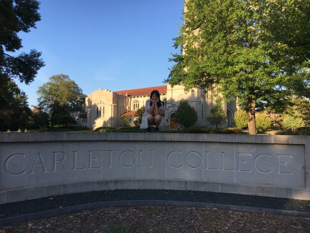 Girl sitting on a college sign post