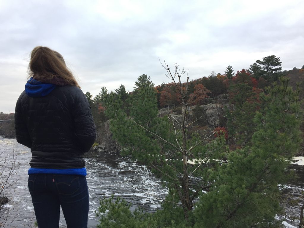 girl looking over river and rocks