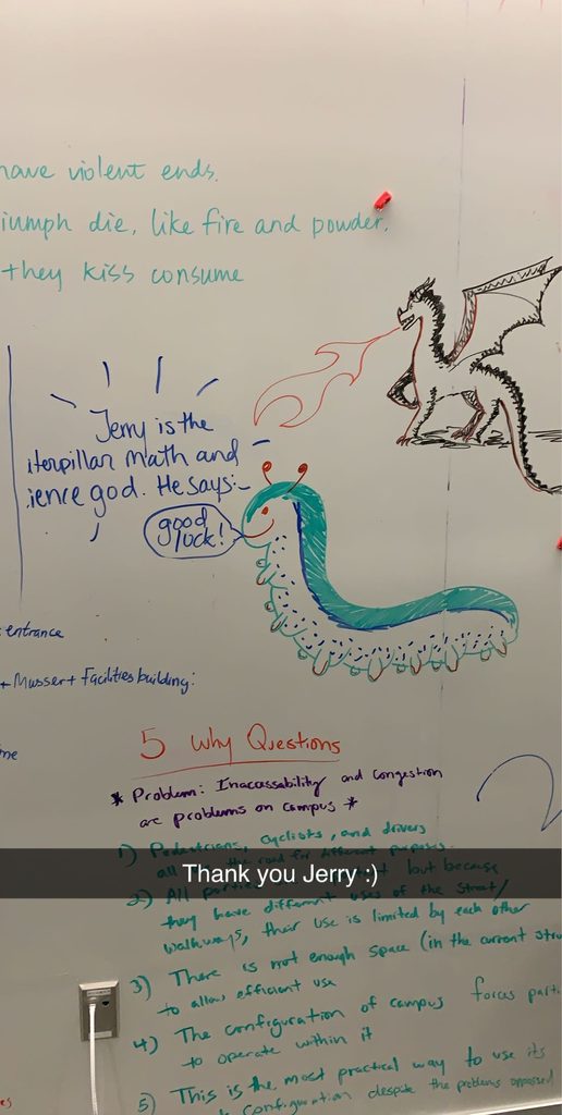 A portion of The Ground State's whiteboard wall with a drawing of a caterpiller beside the caption "Jerry is the caterpillar math and science god. He says 'good luck!'"
