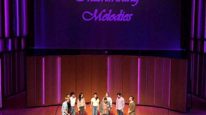 Indoor, 9 students standing on stage and performing a song