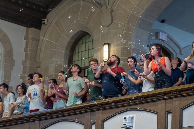 Students blowing bubbles down onto the professors during opening convocation
