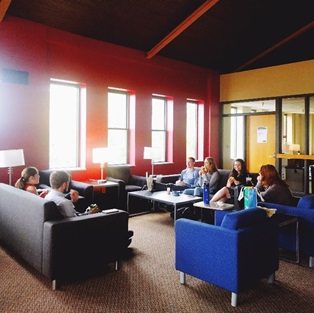 full color photo of students eating lunch together on couches