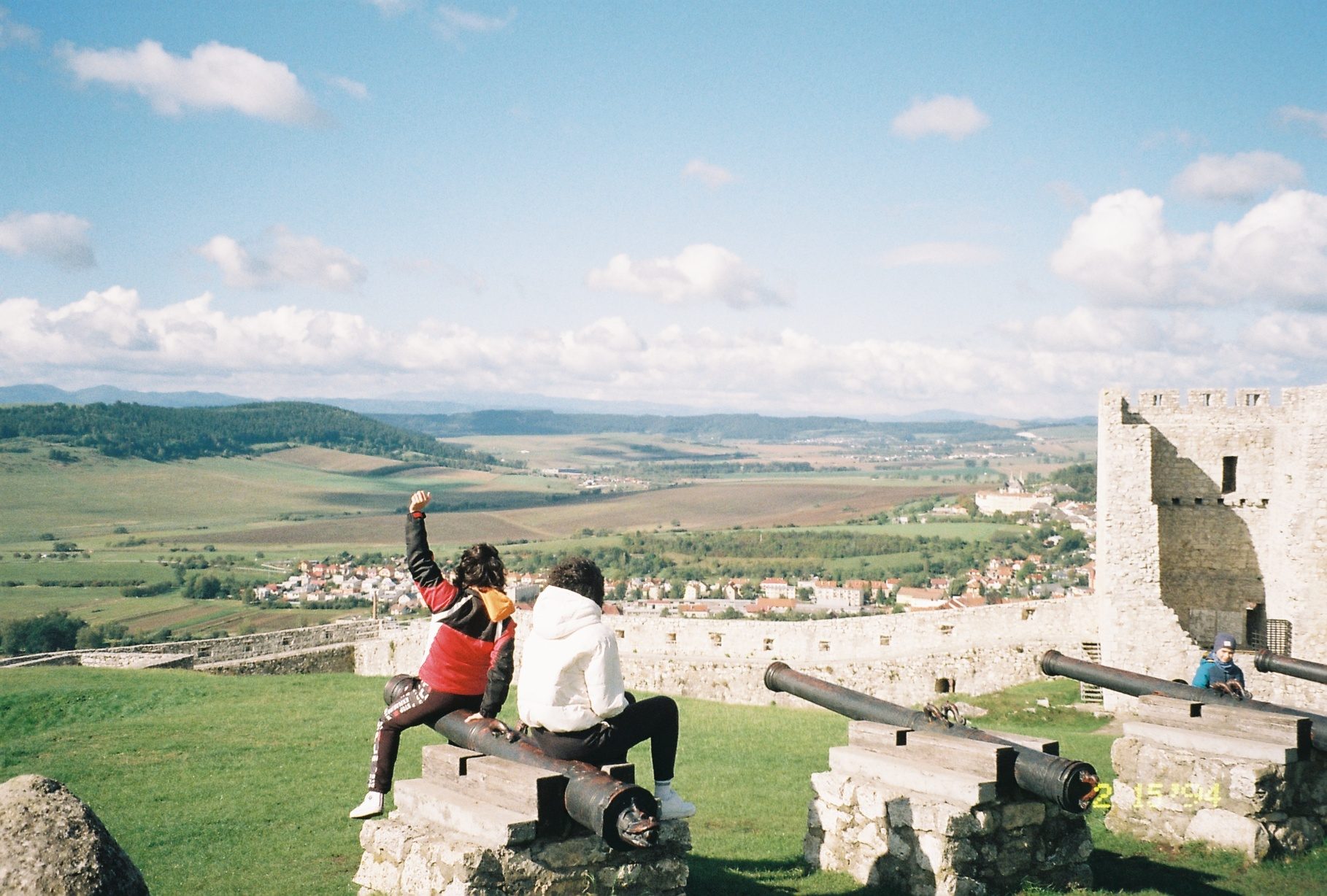 Two students sit on a canon, admiring the view from the castle.