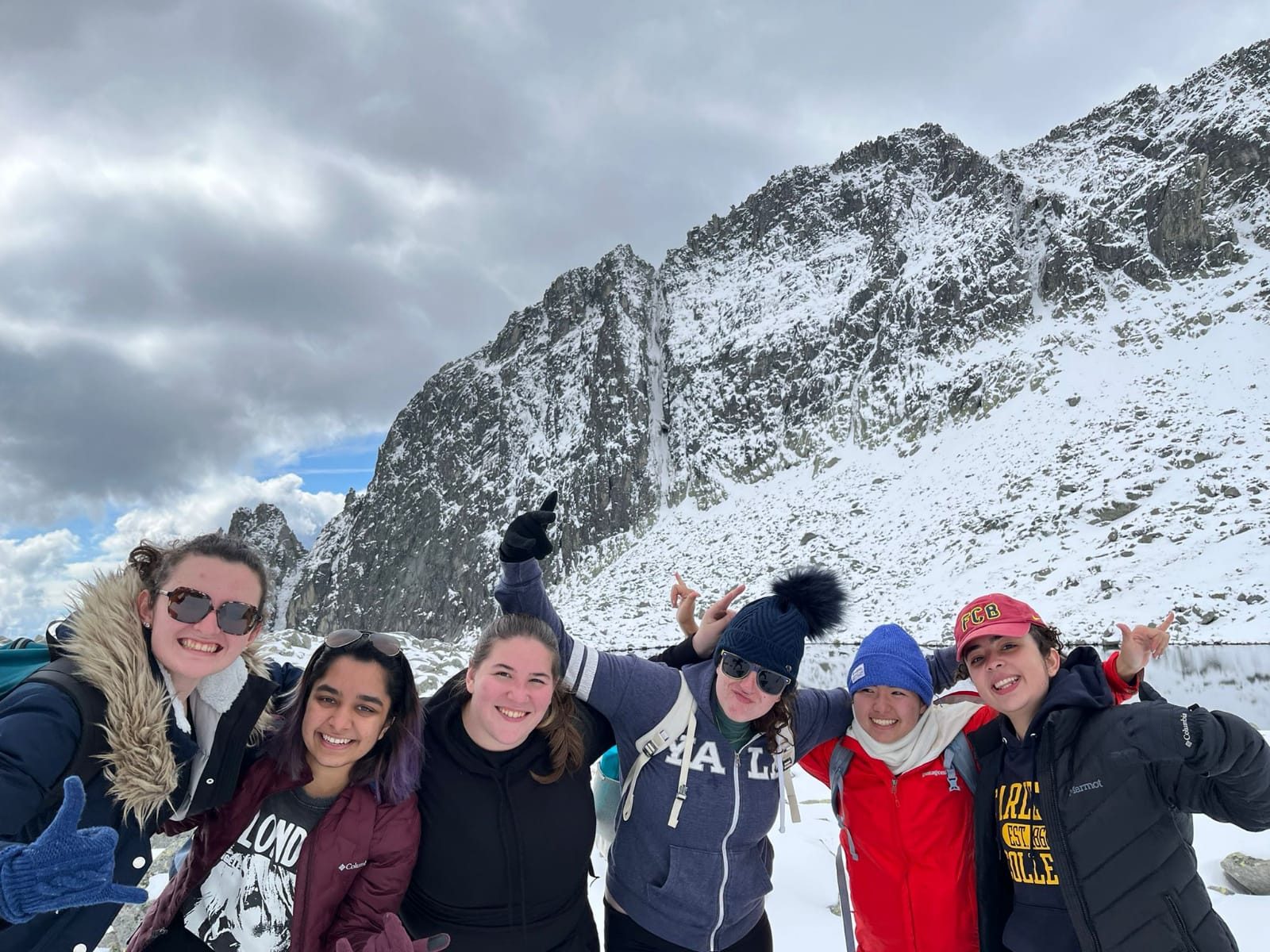 Students celebrate at the top of a snowy mountain.
