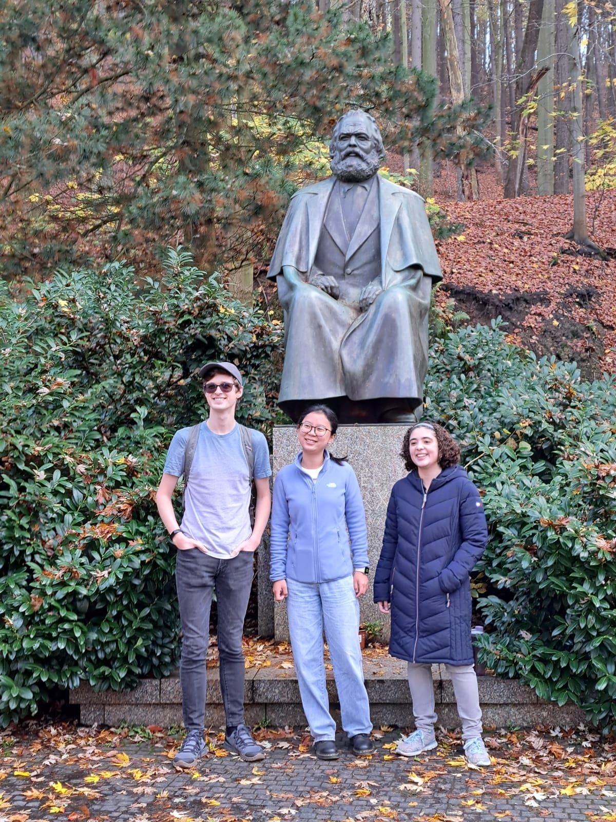 Students stand next to a Karl Marx statue.