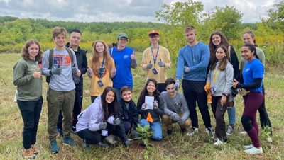 Group 29 stands around a newly planted tree