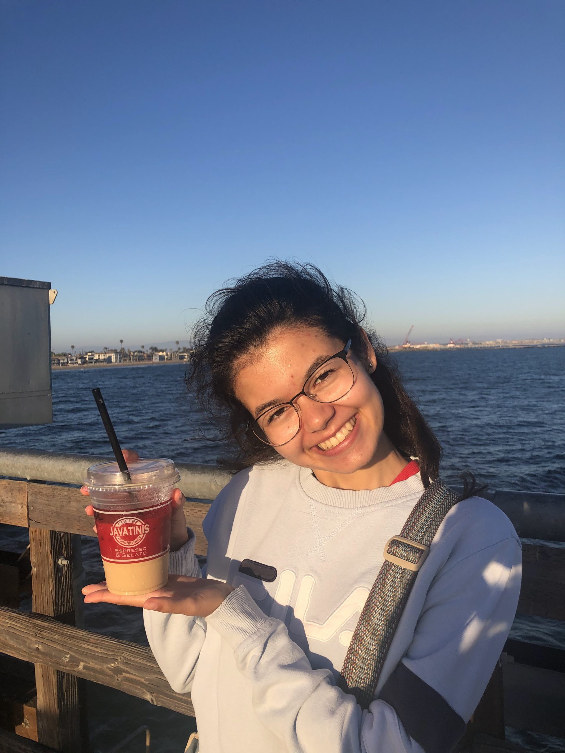 Student poses with a coffee on the Seal Beach pier