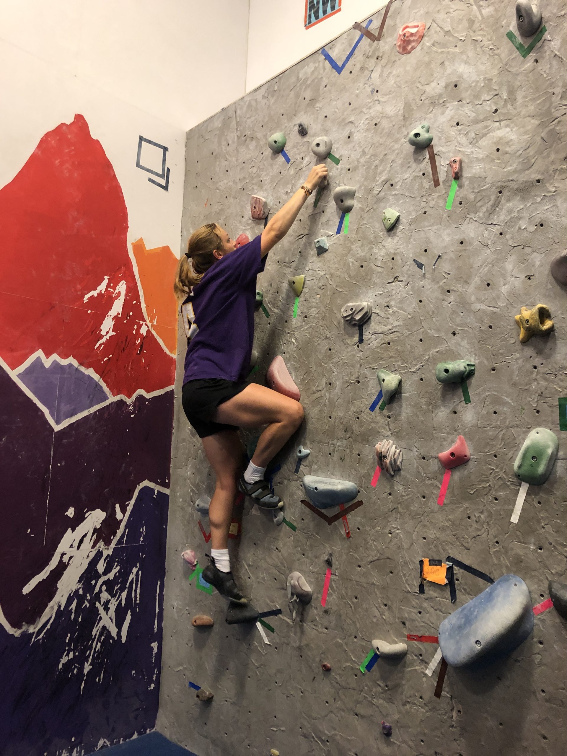 Person wearing purple shirt climbs on wall
