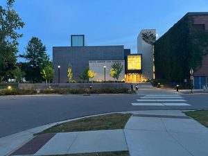 A front view of The Weitz Center at dusk. The windows inside are lit, but the street outside is dark.