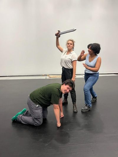 Three students pose for a photo as they are rehearsing.