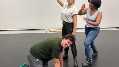 Three students pose for a photo as they are rehearsing.