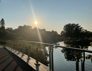 A sunset over the lake, taken from a bridge, with trees in the background.