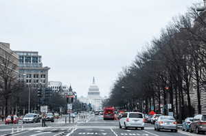 A wide view looking down a street filled with traffic on a rainy day at the Capitol Building in Washington, DC.