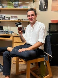 One of Defne's friends sits in a dorm room chair and drinks a soda