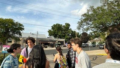 A group of international students in ISO week stand in a parking lot, talking.
