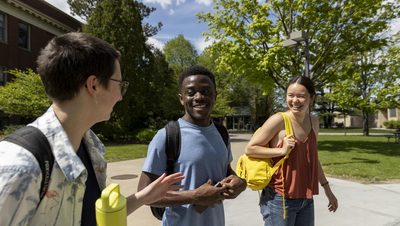 Three students chat and laugh on their way to class.