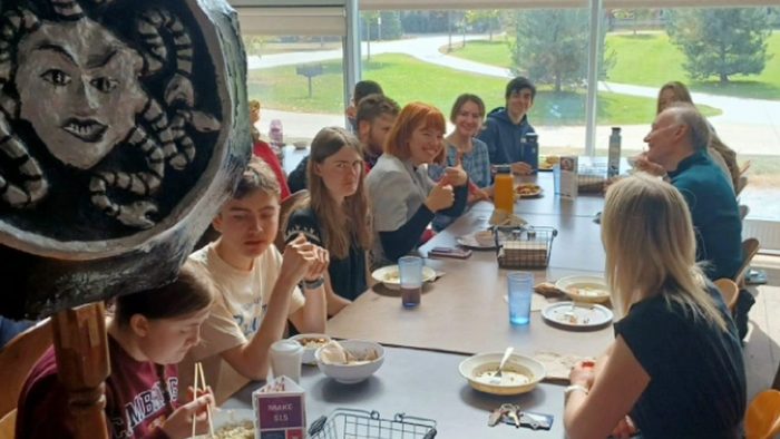 Students eating lunch below a sign with Medusa's head on it