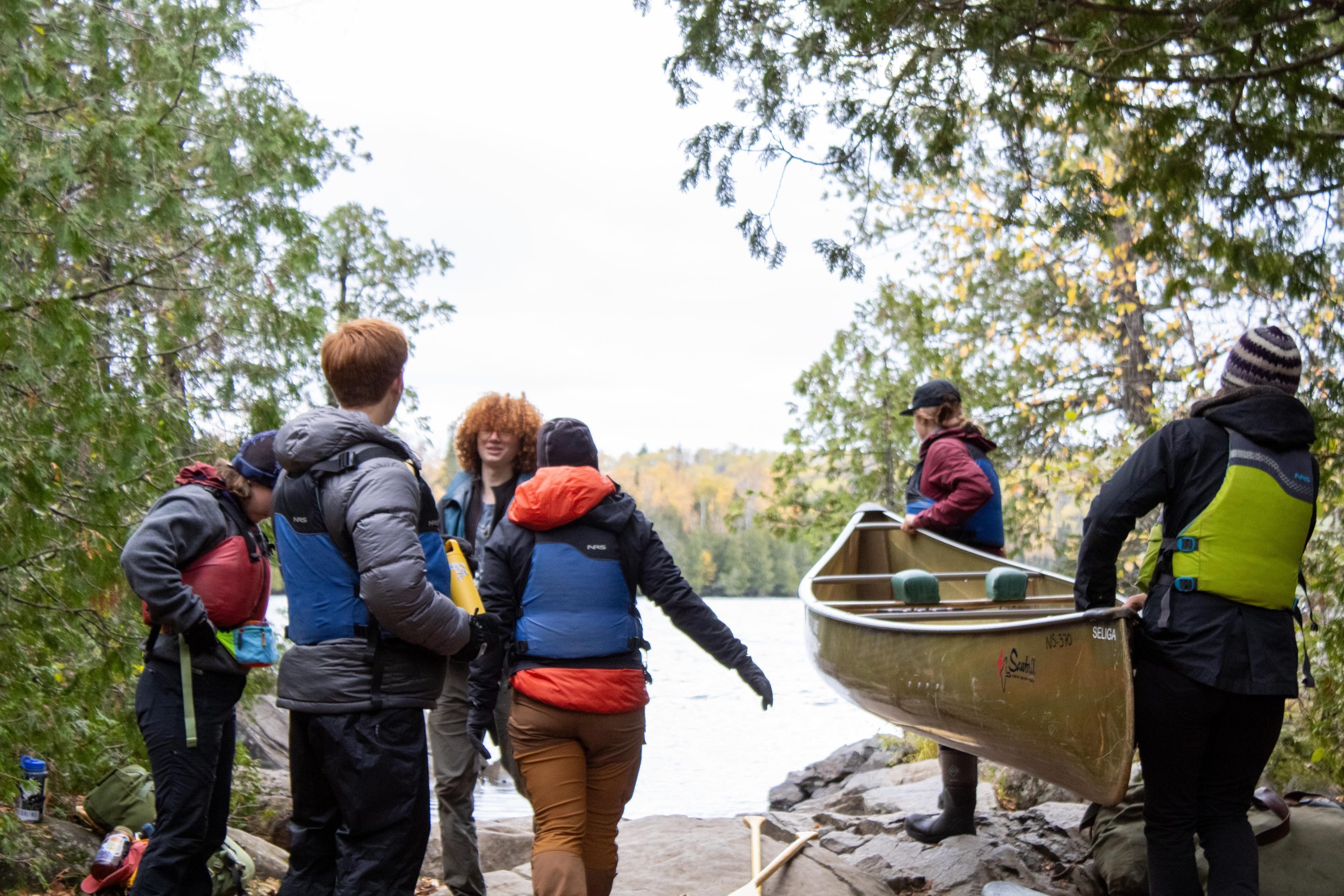 people standing around a canoe at a portage