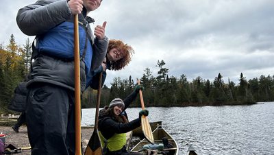three people smiling in a canoe