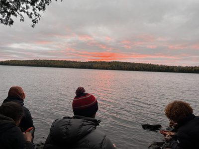 four people sitting in front of a sunset