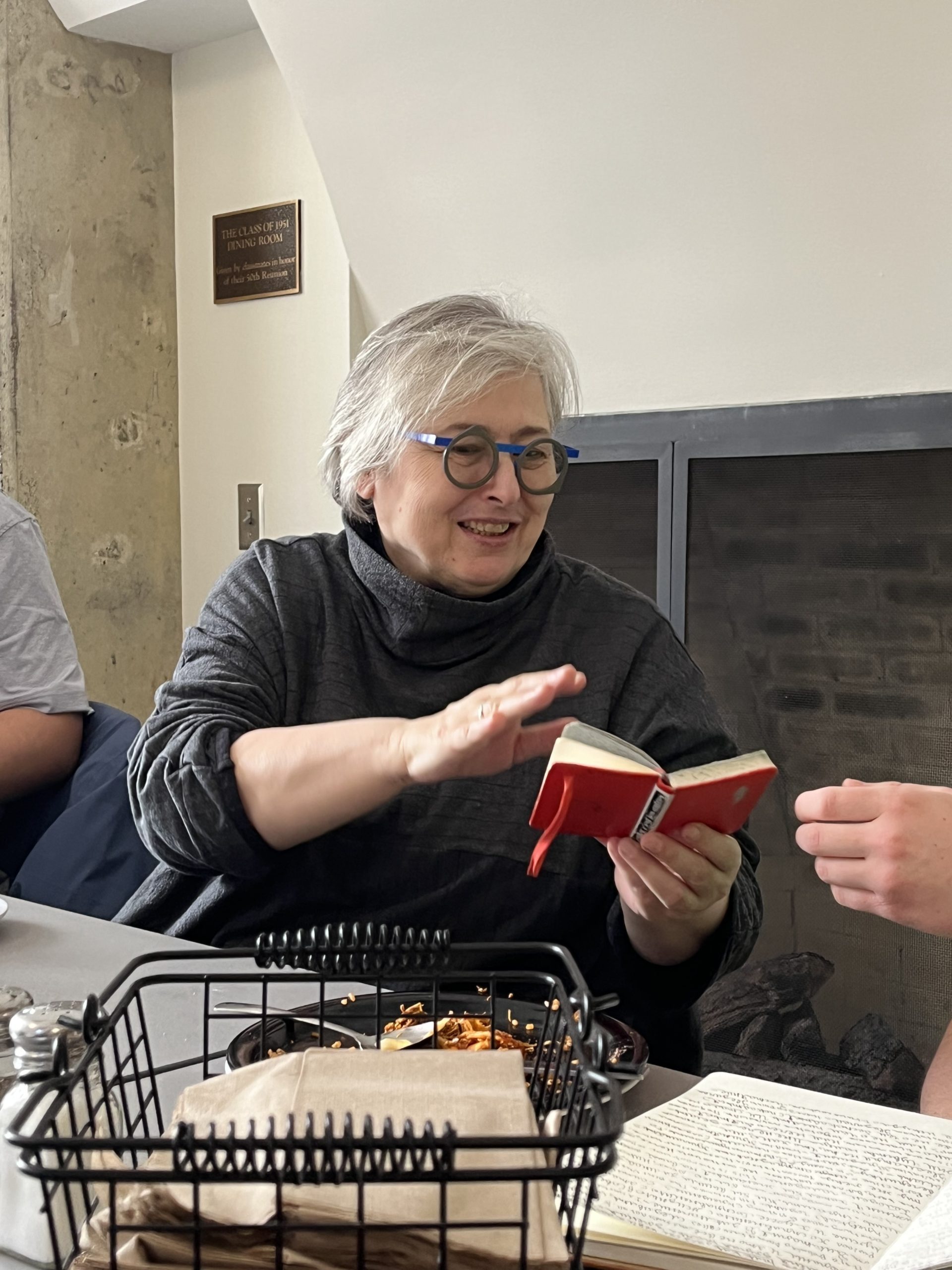 Anna smiles gleefully at a tiny red notebook