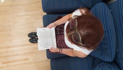 Birds-eye view of a student reading a book on a couch.