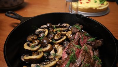 A close-up of a pan with mushrooms and a cooked steak, all well-seasoned.