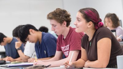 Students take notes during a lecture in an Anderson Hall classroom.