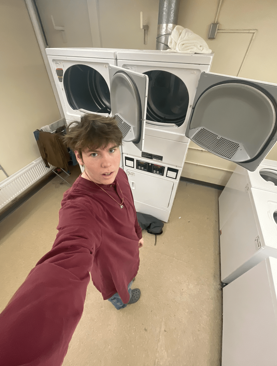 Felix stands in the Goodhue basement in front of 4 washers and 4 dryers