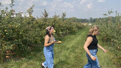 Two girls walking in apple orchard