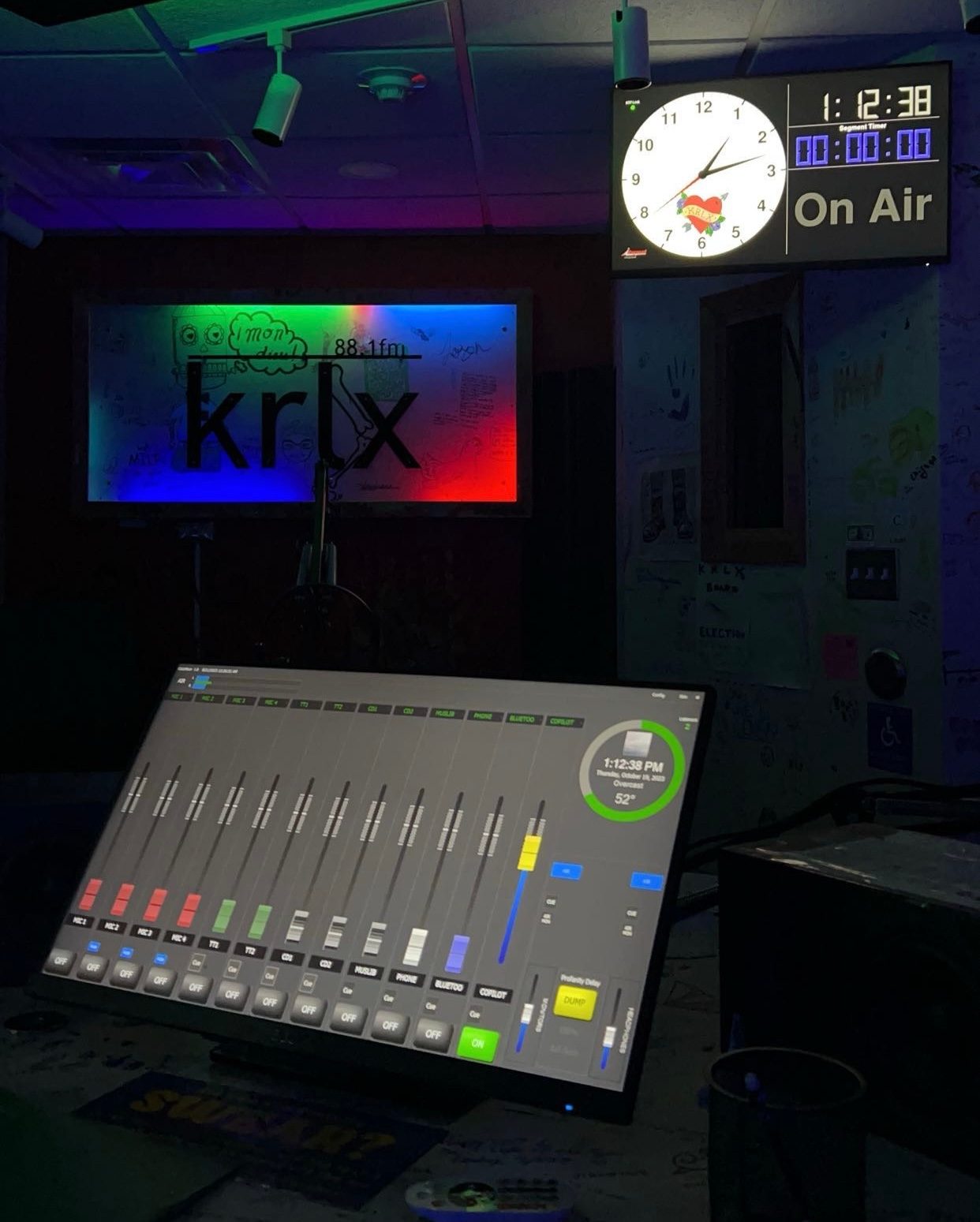 Dark room with KRLX sign with LED lights and a screen with buttons