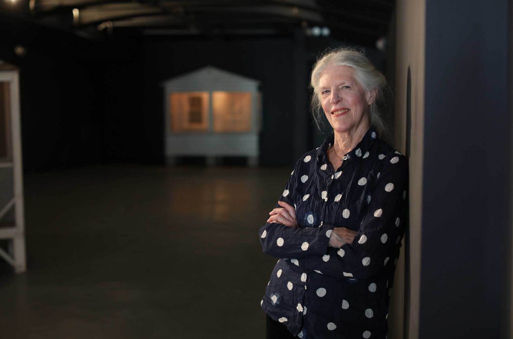 donna dennis leaning against a wall in front of her sculpture