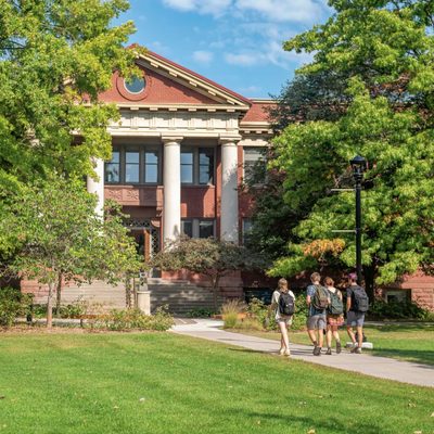 students walking towards a campus building on a fall day