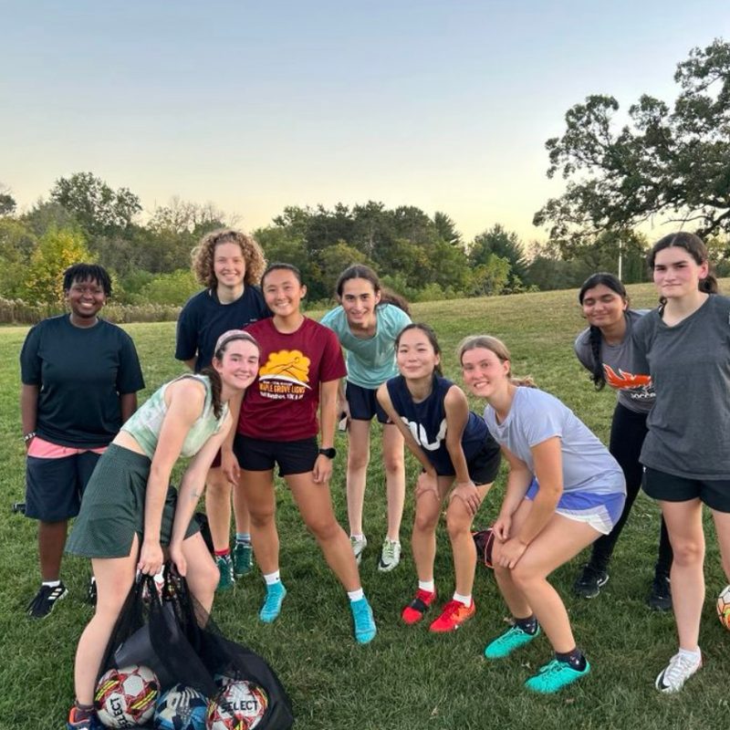 People from the Womxn's club soccer team at practice standing by the hill of three oaks.