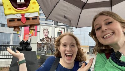 Two students smiling in front of a SpongeBob statue