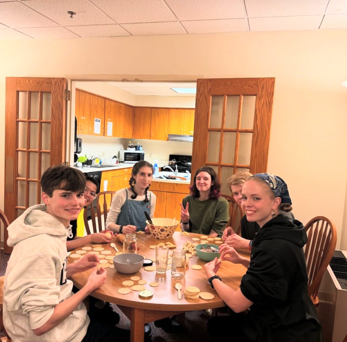 People sitting around a table making dumplings