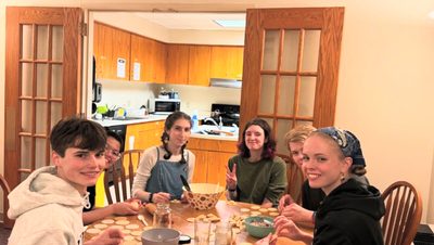 People sitting around a table making dumplings