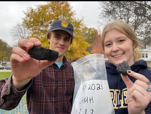 Two students holding up a rock found in an archaeology dig