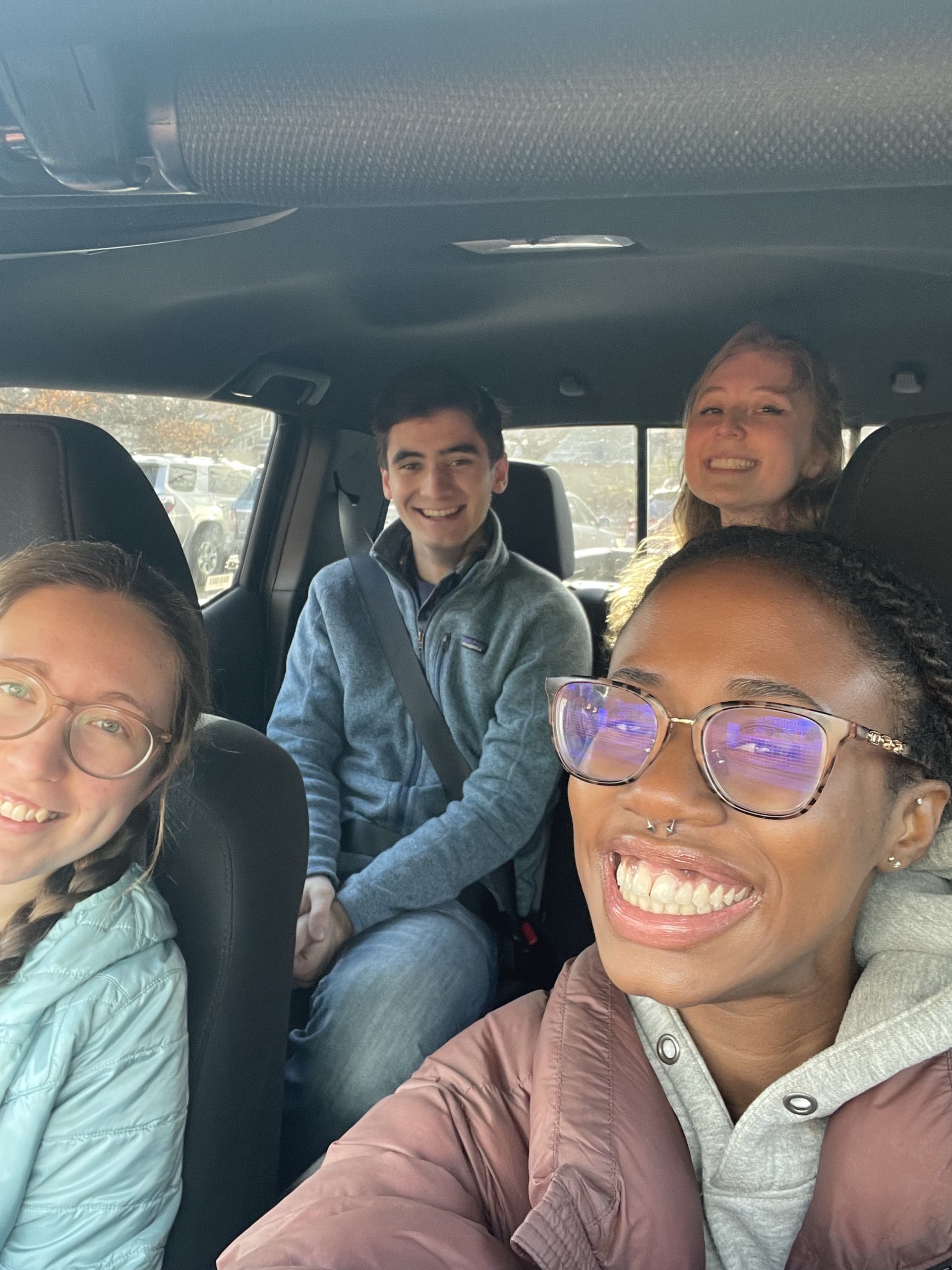 Four students smiling in a car