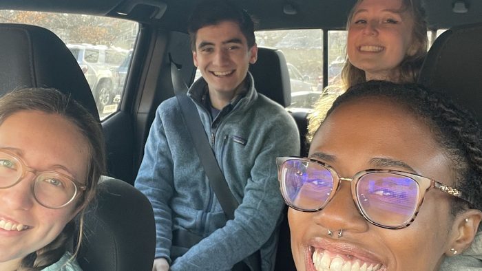 Four students smiling in a car