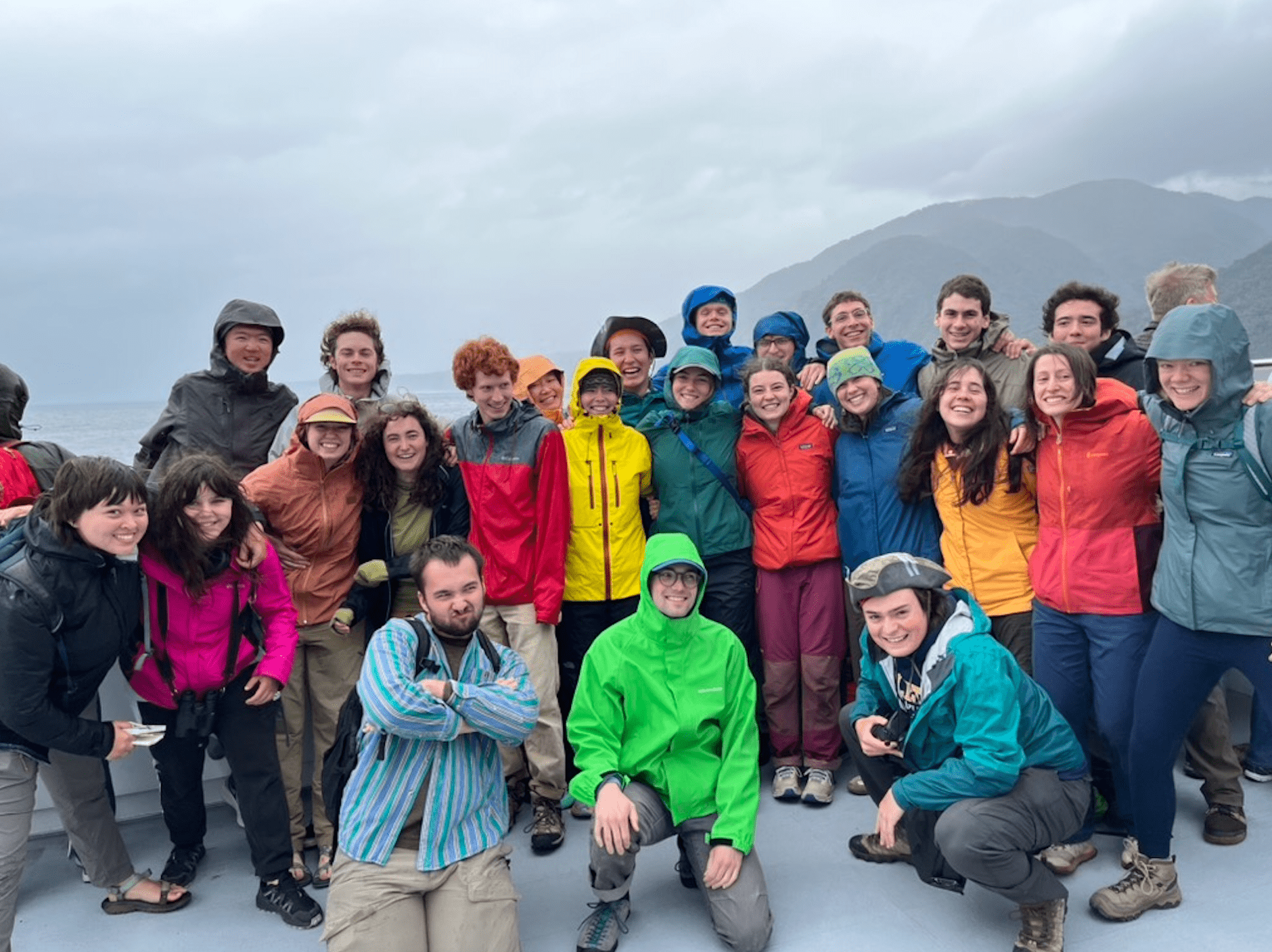 People standing in rain jackets on a boat