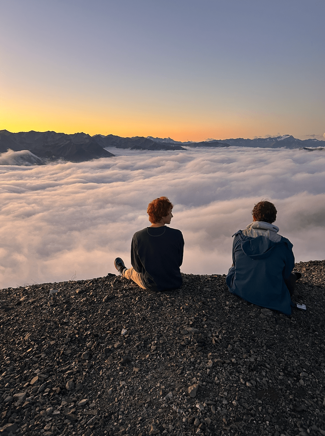 People sitting on a mountain above the clouds
