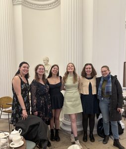 Six people smiling at the camera at high tea