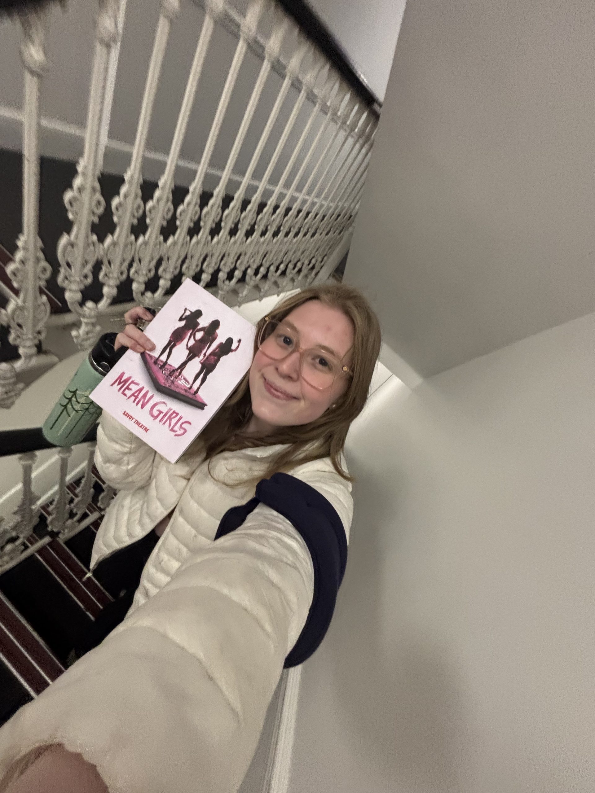 A girl holding a "Mean Girls" program
