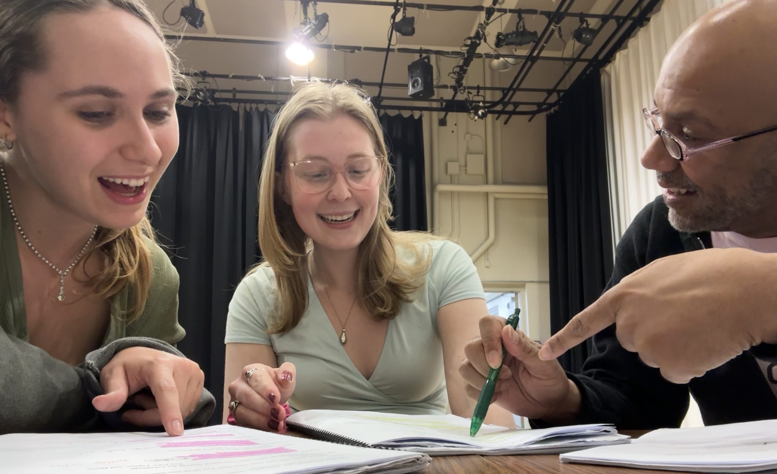 Two students looking at their scripts with a teacher