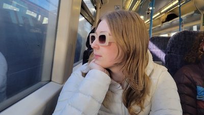 A girl with sunglasses staring out the window of the train